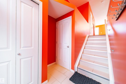 Tiled flooring, white paneled doors, staircase with white risers, and a wall-mounted coat rack - #31 460 Hemingway Rd Nw, Edmonton, AB 