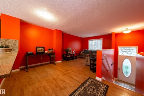 Wood-finish flooring throughout, featuring a breakfast bar with a tile backsplash, and a front entry door with decorative glass - #31 460 Hemingway Rd Nw, Edmonton, AB 
