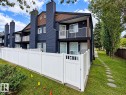 Multi-level exterior featuring dark-toned siding, white balcony railings, and a private white fence - 3526 42 Street Nw, Edmonton, AB 