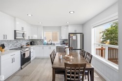 Modern kitchen featuring white cabinetry, stainless steel appliances, mosaic tile backsplash, wood-finish flooring, and recessed lighting - 