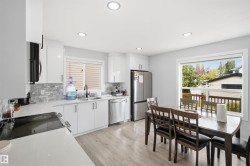 Modern kitchen featuring white cabinetry, stainless steel appliances, a tile backsplash, and recessed lighting - 