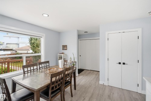 Bright interior with recessed lighting, wood-finish flooring, a large picture window, and white bi-fold doors with matte black hardware - 2122 37 Avenue Nw, Edmonton, AB 