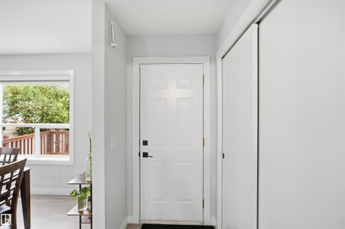 Entryway featuring a paneled door with matte black hardware, adjacent sliding closet doors, and wood-finish flooring - 2122 37 Avenue Nw, Edmonton, AB 