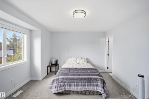 Carpeted room with a large window, a flush mount ceiling light, and a white interior door with black hardware - 2122 37 Avenue Nw, Edmonton, AB 