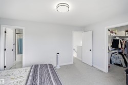 Carpeted room featuring a built-in closet with shelving, a ceiling-mounted light fixture, and a doorway revealing a bathroom with a shower-tub combination - 