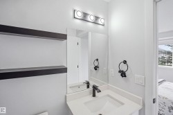 Vanity with a white countertop and integrated sink, matte black faucet, wall-mounted mirror, and overhead vanity lighting - 