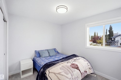Neutral wall paint, carpet flooring, a window with white trim, and a ceiling-mounted light fixture - 2122 37 Avenue Nw, Edmonton, AB 