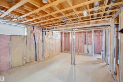 Unfinished basement with exposed wood joists, concrete flooring, insulated perimeter walls, and framed interior partitions - 
