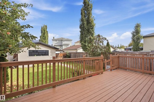 Expansive wood-finish deck with integrated railing, leading to a manicured lawn area - 2122 37 Avenue Nw, Edmonton, AB 
