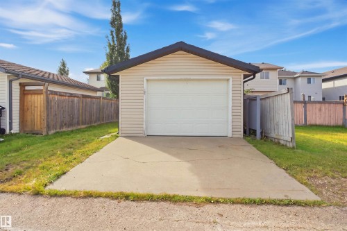 Detached garage with a paneled garage door, light-colored siding, and a concrete driveway - 2122 37 Avenue Nw, Edmonton, AB 