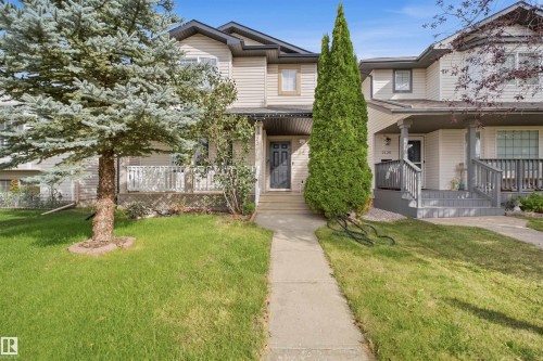 Two-story townhome with light-toned siding, a covered front porch, and a dedicated walkway - 2122 37 Avenue Nw, Edmonton, AB 