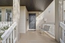 Covered porch with wood-finish flooring, white railing, and exterior wall sconce - 2122 37 Avenue Nw, Edmonton, AB 