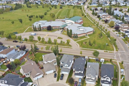 Residential neighborhood with mature trees and a nearby community building featuring a large parking area - 2122 37 Avenue Nw, Edmonton, AB 