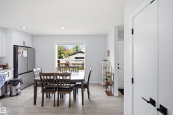 Recessed ceiling lighting, wood-finish flooring, white cabinetry, stainless steel refrigerator, and white interior doors with matte black hardware - 
