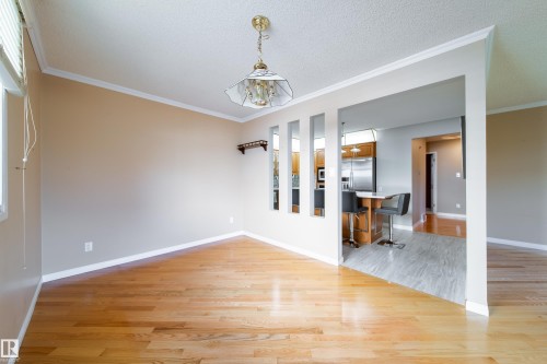 Hardwood flooring, crown molding, and a chandelier illuminate a spacious interior - 10438 32A Avenue Nw, Edmonton, AB 
