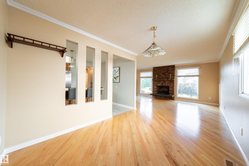 Hardwood flooring throughout, brick-clad fireplace, multiple large windows, coved ceilings, and crown molding - 10438 32A Avenue Nw, Edmonton, AB 