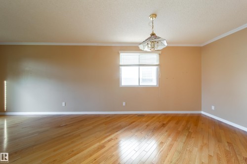 Wood-finish flooring, neutral wall tones, window with horizontal blinds, and a decorative ceiling light fixture - 10438 32A Avenue Nw, Edmonton, AB 