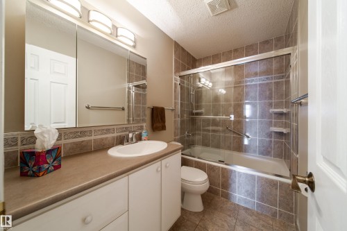 Bathroom featuring a full-width vanity with an integrated sink, white cabinetry, and a framed mirror - 10438 32A Avenue Nw, Edmonton, AB 