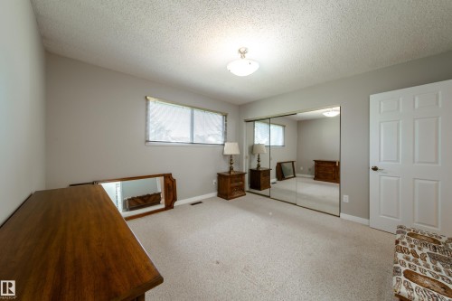 Light-toned wall paint, textured ceiling, carpeting, and a mirrored closet door - 10438 32A Avenue Nw, Edmonton, AB 