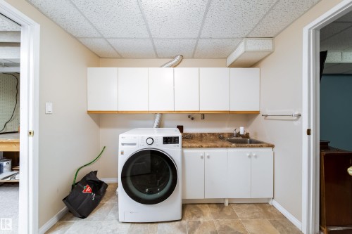 Laundry area featuring upper and lower cabinetry, a utility sink, and a laminate countertop - 10438 32A Avenue Nw, Edmonton, AB 