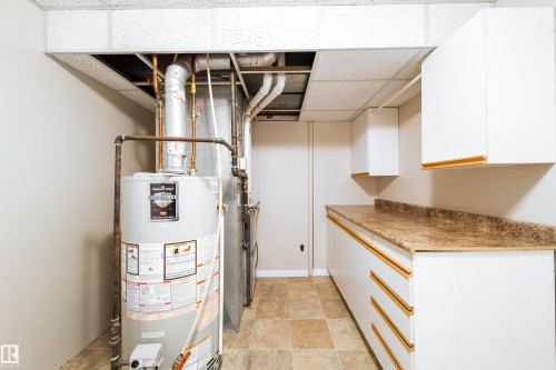 Tile flooring, white cabinetry with gold-tone hardware, and a laminate countertop - 10438 32A Avenue Nw, Edmonton, AB 