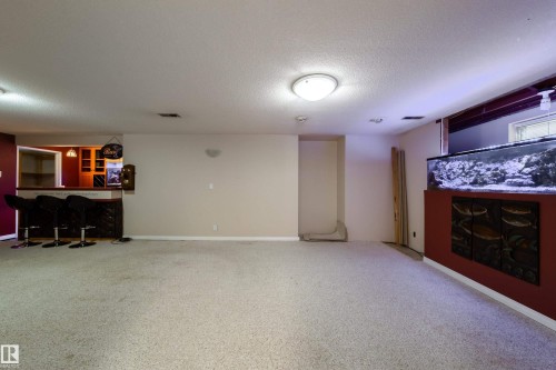 Expansive carpeted area featuring a built-in wet bar with cabinetry and an integrated aquarium display - 10438 32A Avenue Nw, Edmonton, AB 