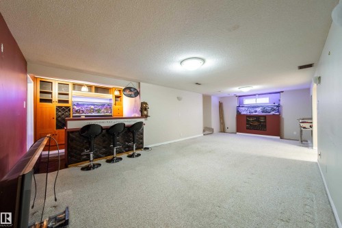 Built-in bar with wood-finish cabinetry, integrated wine storage, and a textured bar front - 10438 32A Avenue Nw, Edmonton, AB 