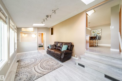 Light wood-finish flooring with multiple windows and track lighting - 10438 32A Avenue Nw, Edmonton, AB 