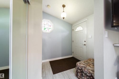 Entryway featuring a white paneled door with an arched transom, an octagonal window with decorative glass, and wood-finish flooring - 10438 32A Avenue Nw, Edmonton, AB 