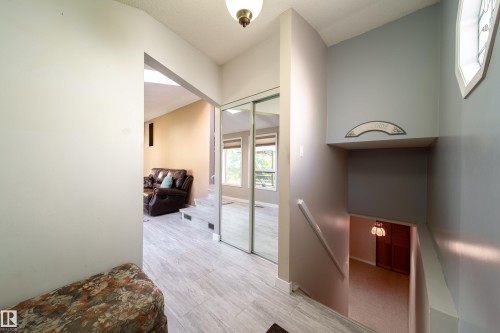Light wood-finish flooring, mirrored closet doors, and a decorative stained glass window - 10438 32A Avenue Nw, Edmonton, AB 