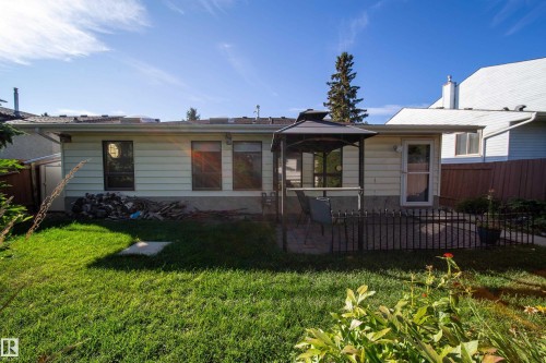 Expansive backyard featuring a green lawn, concrete patio, and a covered gazebo - 10438 32A Avenue Nw, Edmonton, AB 