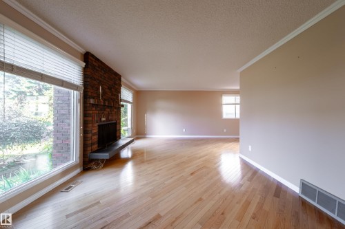 Warm wood flooring, a brick-faced fireplace with a hearth, and large windows - 10438 32A Avenue Nw, Edmonton, AB 