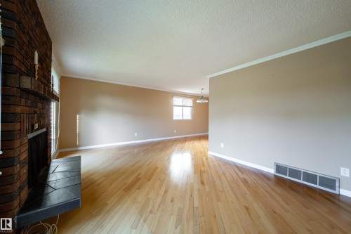 Wood-finish flooring, brick fireplace surround, mantel, crown molding, and window with blinds - 10438 32A Avenue Nw, Edmonton, AB 