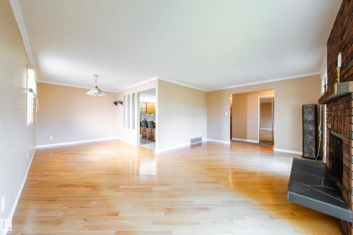 Hardwood flooring, brick fireplace with a slate hearth, crown molding, cased openings, and a ceiling-mounted light fixture - 10438 32A Avenue Nw, Edmonton, AB 