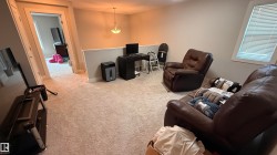 Carpeted interior space featuring a half-wall partition, an attached ceiling light fixture, and a window with blinds - 