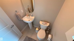 Pedestal sink with chrome faucet, oval mirror, and tile flooring - 