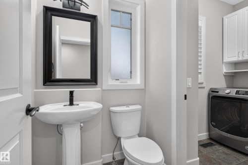 Pedestal sink with matte black faucet, framed mirror, and built-in upper cabinetry - 904 Armitage Court Sw, Edmonton, AB 