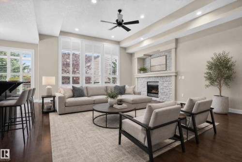 Expansive living area featuring rich wood-finish flooring, a stone-clad fireplace, and recessed lighting - 904 Armitage Court Sw, Edmonton, AB 