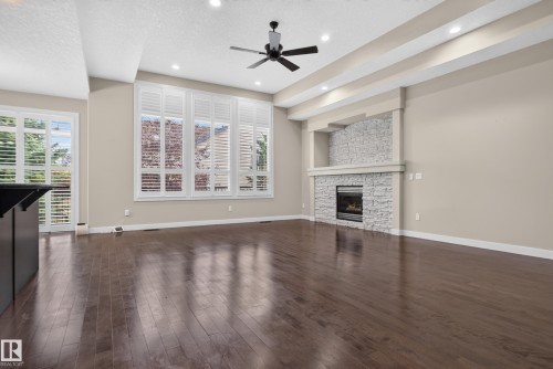Hardwood flooring, stone-clad fireplace with mantel, recessed ceiling lighting, ceiling fan, and plantation shutters - 904 Armitage Court Sw, Edmonton, AB 