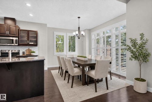 Dark wood-finish flooring complements the modern kitchen island with a stone-finish countertop - 904 Armitage Court Sw, Edmonton, AB 