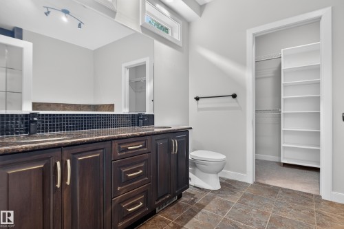 Dual vanity with dark wood cabinetry, integrated sinks, and dark tile backsplash - 904 Armitage Court Sw, Edmonton, AB 
