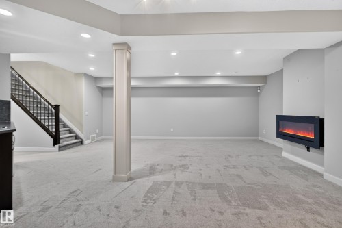 Expansive finished lower level featuring recessed lighting, a wall-mounted electric fireplace, and plush carpet flooring - 904 Armitage Court Sw, Edmonton, AB 