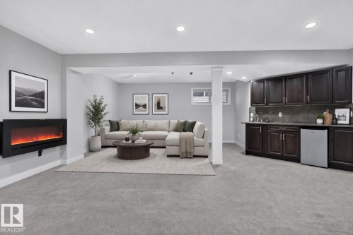 Recessed lighting, wall-mounted electric fireplace, built-in wet bar with dark wood-finish cabinetry, under-counter refrigeration, and plush carpet flooring - 904 Armitage Court Sw, Edmonton, AB 