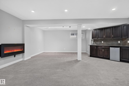 Recessed lighting, electric fireplace, built-in cabinetry, wet bar with sink, and compact refrigerator - 904 Armitage Court Sw, Edmonton, AB 