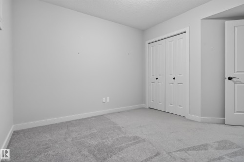 Neutral wall paint, white trim, light grey carpet, bi-fold closet doors, and a paneled door - 904 Armitage Court Sw, Edmonton, AB 