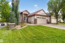 Siding exterior with brick accents, attached two-car garage, mature landscaping, and a stone pillar feature - 904 Armitage Court Sw, Edmonton, AB 