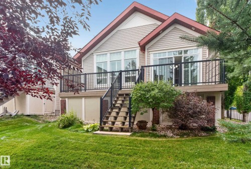 Rear exterior with a raised deck, black metal railings, and dual sliding glass doors - 904 Armitage Court Sw, Edmonton, AB 
