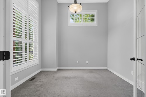 Neutral gray wall color, a contemporary light fixture, and plush carpet flooring - 904 Armitage Court Sw, Edmonton, AB 