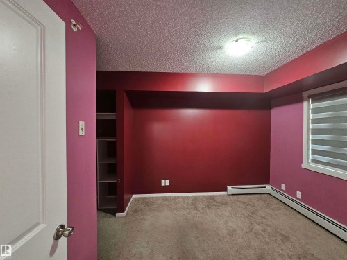 Built-in shelving, window with blinds, wall-mounted heating units, and overhead lighting fixture - #421 5816 Mullen Place Nw, Edmonton, AB 