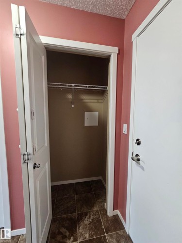 Entryway with tiled flooring, white paneled doors, and a built-in closet with wire shelving - #421 5816 Mullen Place Nw, Edmonton, AB 
